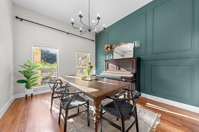 dining space with a chandelier, a decorative wall, and light wood finished floors