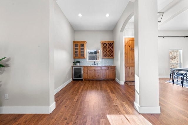 bar with decorative backsplash, hardwood / wood-style flooring, wine cooler, and sink