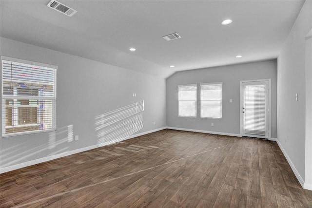 spare room with dark wood-type flooring and lofted ceiling