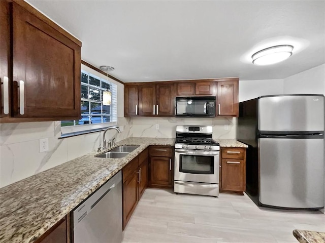 kitchen featuring light stone counters, sink, and stainless steel appliances