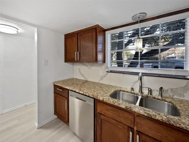 kitchen featuring light stone countertops, backsplash, sink, dishwasher, and hanging light fixtures