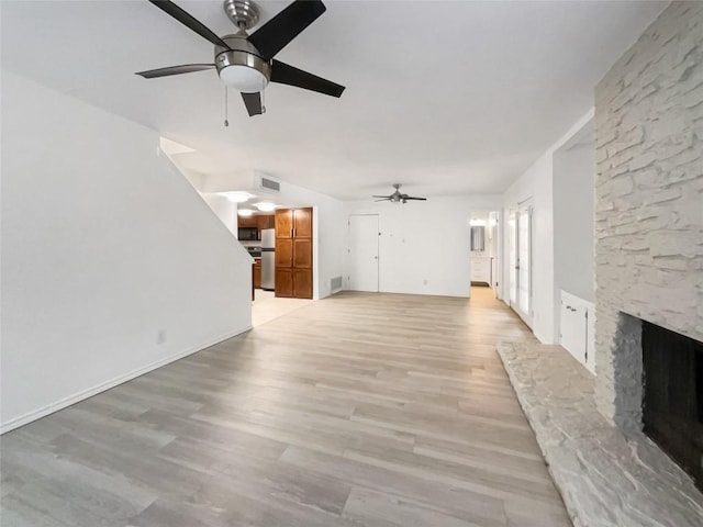 3424 Clarksburg Dr, Austin, TX 78745 - unfurnished living room with ceiling fan, a stone fireplace, and light wood-type flooring