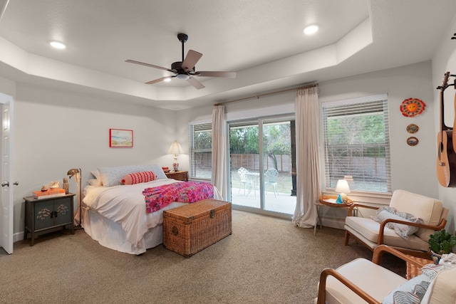 carpeted bedroom with access to outside, a raised ceiling, and ceiling fan