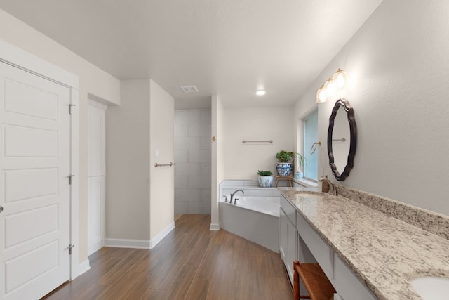 bathroom with vanity, wood-type flooring, and a tub to relax in