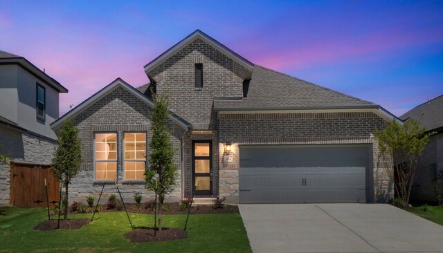 view of front of house with concrete driveway, a yard, brick siding, and a garage