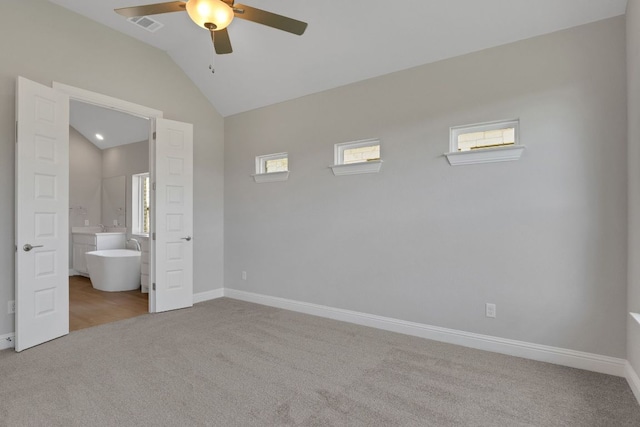 unfurnished bedroom featuring baseboards, ensuite bathroom, carpet floors, visible vents, and lofted ceiling