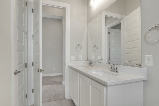 bathroom featuring double vanity, baseboards, and a sink