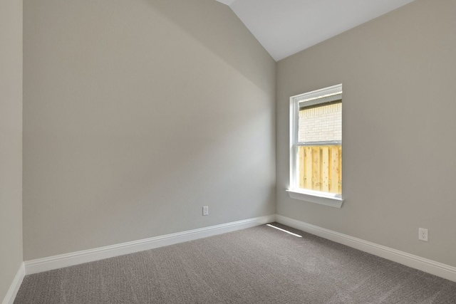 empty room with baseboards, dark colored carpet, and lofted ceiling