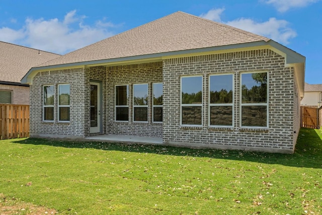rear view of property featuring a lawn, fence, a patio area, and brick siding
