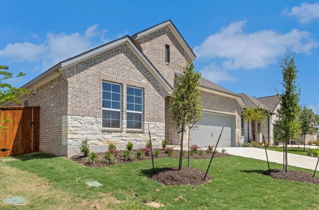 view of front facade with brick siding, a front yard, an attached garage, and concrete driveway