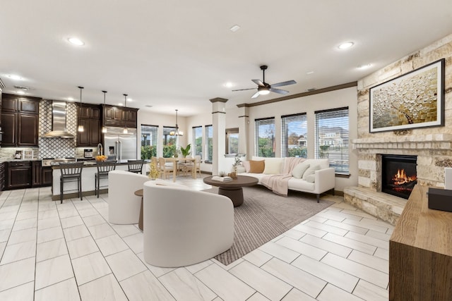 living room featuring ceiling fan, ornamental molding, and a fireplace