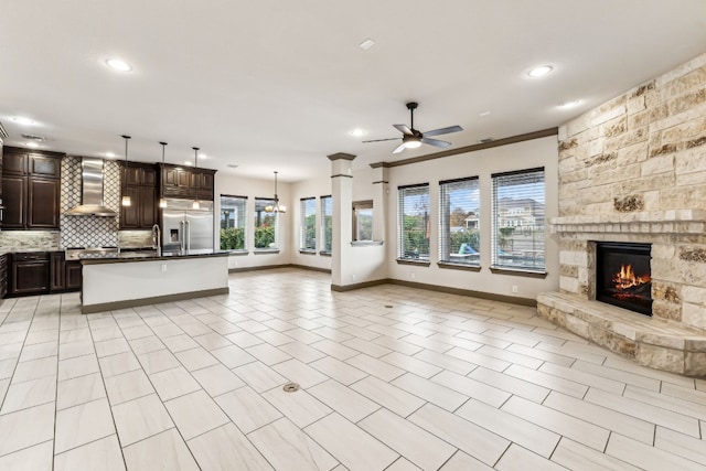 unfurnished living room featuring sink, ceiling fan, crown molding, and a fireplace