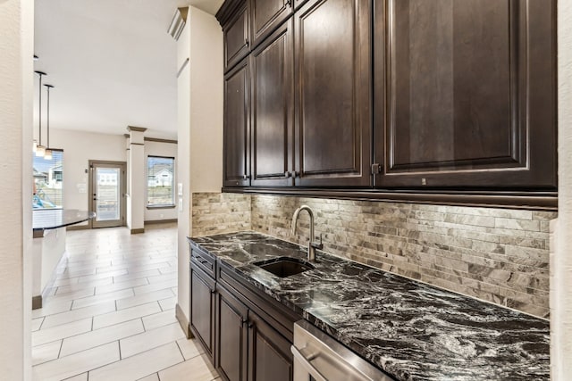 kitchen featuring decorative backsplash, sink, dark stone countertops, hanging light fixtures, and light tile patterned flooring