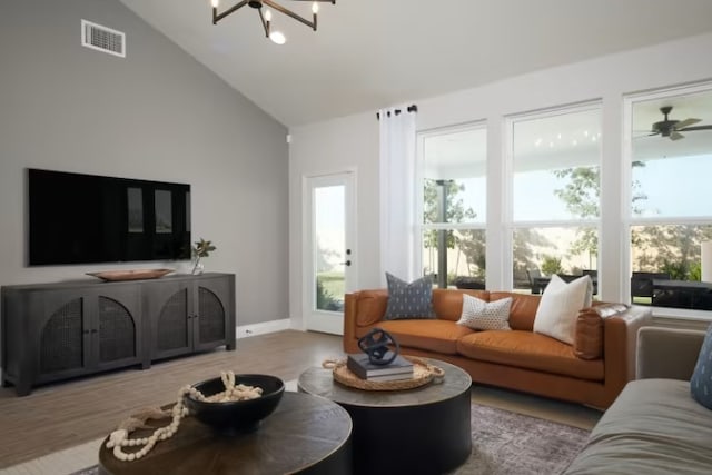 living room with ceiling fan with notable chandelier, light hardwood / wood-style floors, and lofted ceiling