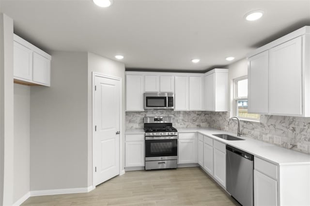 kitchen featuring tasteful backsplash, sink, light wood-type flooring, appliances with stainless steel finishes, and white cabinets