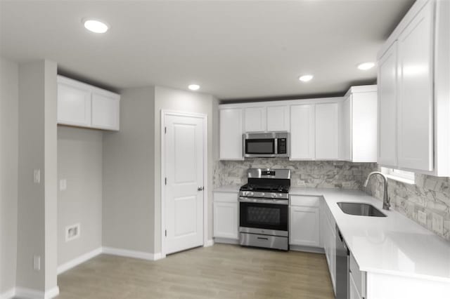 kitchen featuring backsplash, sink, light hardwood / wood-style flooring, stainless steel appliances, and white cabinets