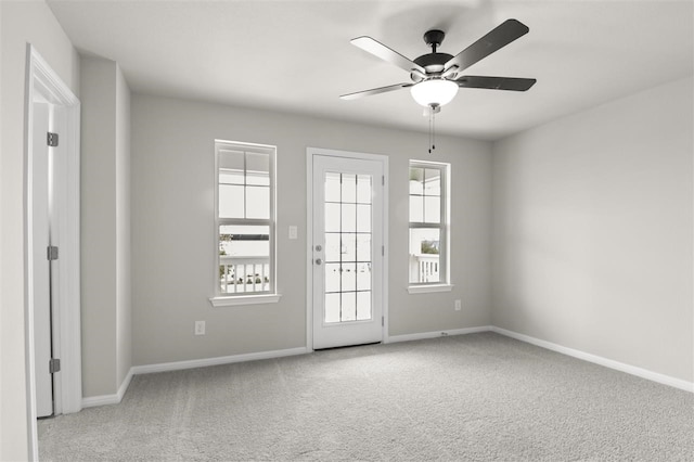 carpeted empty room with ceiling fan and a wealth of natural light