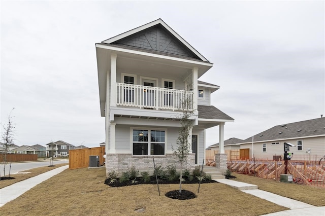 view of front facade with a front yard, central air condition unit, and a balcony