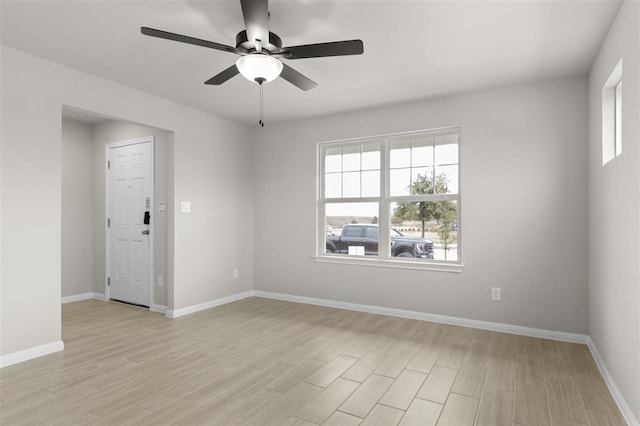 empty room with ceiling fan, a wealth of natural light, and light hardwood / wood-style floors