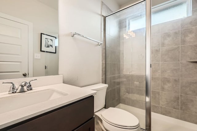 bathroom with vanity, a shower with shower door, and toilet