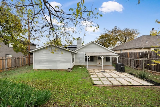 back of house with solar panels, a yard, and a patio area