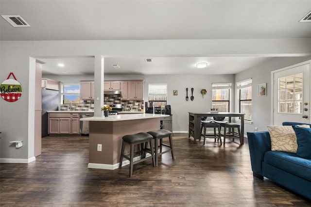 kitchen featuring a center island, light brown cabinets, a kitchen breakfast bar, tasteful backsplash, and stainless steel appliances