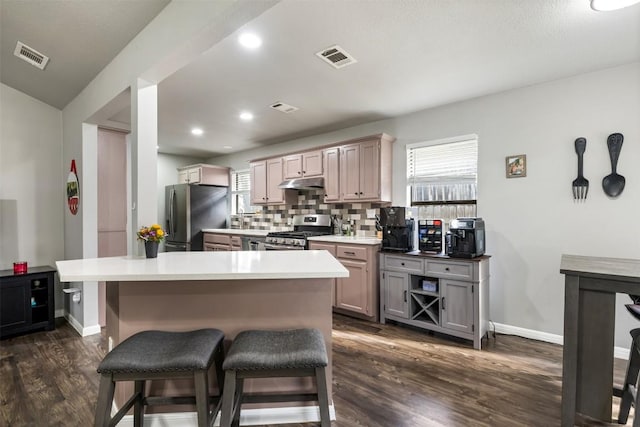 kitchen with a kitchen breakfast bar, tasteful backsplash, stainless steel appliances, dark wood-type flooring, and a center island