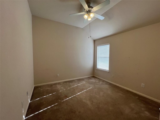 empty room featuring ceiling fan, vaulted ceiling, and dark colored carpet