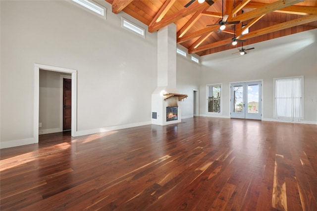 unfurnished living room with french doors, a fireplace, a towering ceiling, and dark hardwood / wood-style floors