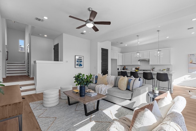 living room featuring ceiling fan, sink, and light wood-type flooring