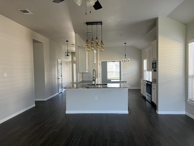 kitchen with appliances with stainless steel finishes, sink, pendant lighting, white cabinets, and a kitchen island