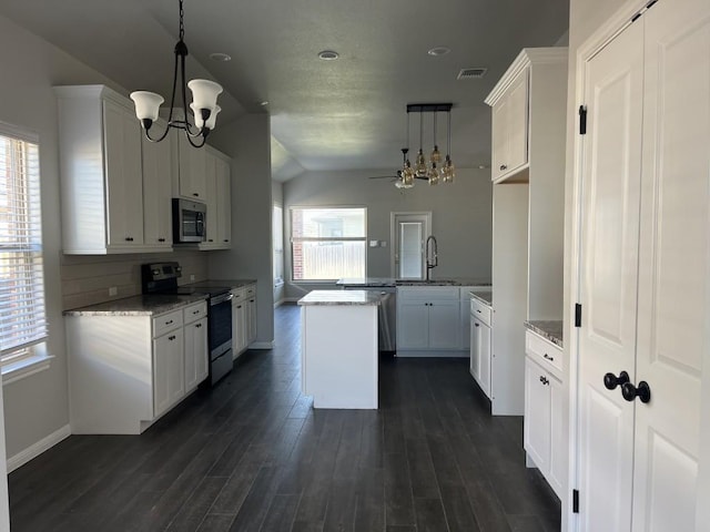 kitchen featuring hanging light fixtures, a wealth of natural light, appliances with stainless steel finishes, white cabinetry, and kitchen peninsula