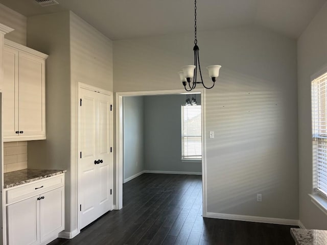 unfurnished dining area with vaulted ceiling, an inviting chandelier, and dark wood-type flooring