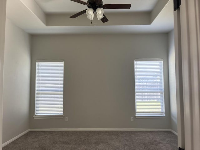 carpeted spare room with a raised ceiling and ceiling fan