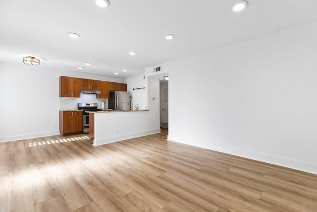 kitchen with light stone countertops, appliances with stainless steel finishes, and light hardwood / wood-style floors