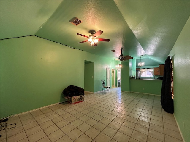 interior space featuring a textured ceiling, ceiling fan, light tile patterned flooring, and vaulted ceiling