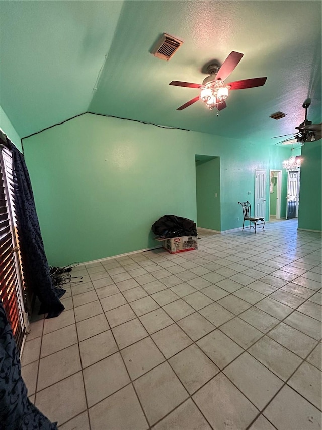 tiled empty room featuring a textured ceiling, ceiling fan, and vaulted ceiling