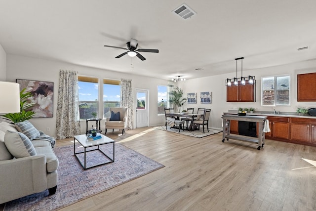 living room with light wood-type flooring, ceiling fan, and sink