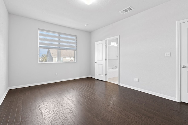 unfurnished bedroom with dark wood-type flooring and connected bathroom