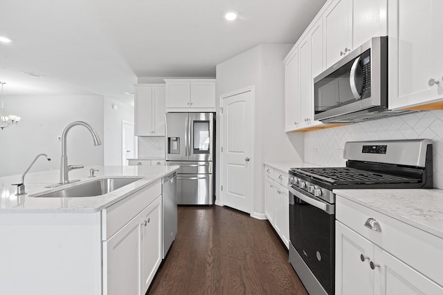 kitchen featuring appliances with stainless steel finishes, decorative light fixtures, tasteful backsplash, white cabinetry, and sink