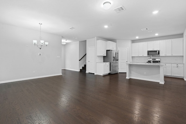 unfurnished living room with an inviting chandelier and dark hardwood / wood-style floors