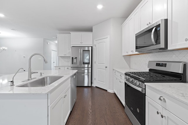 kitchen with tasteful backsplash, appliances with stainless steel finishes, sink, and white cabinets