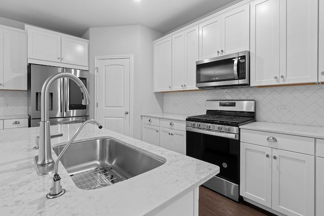 kitchen with light stone countertops, appliances with stainless steel finishes, sink, and white cabinets