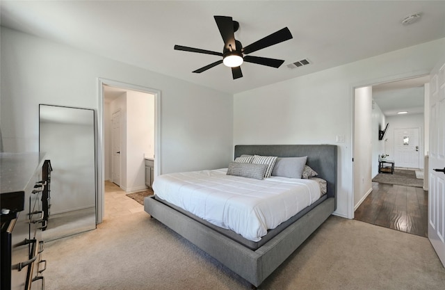 bedroom featuring ensuite bathroom, ceiling fan, and light colored carpet