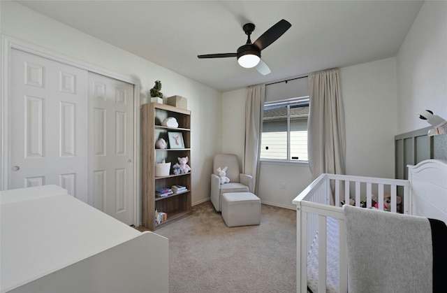 bedroom featuring ceiling fan, light colored carpet, a nursery area, and a closet