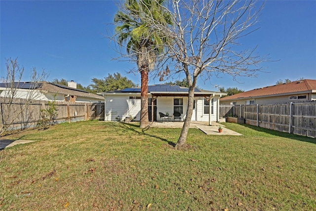 rear view of property with solar panels, a yard, and a patio