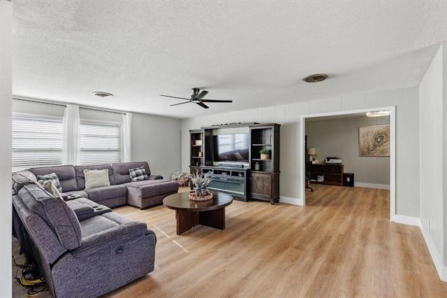 living room with ceiling fan, light wood-type flooring, and a textured ceiling