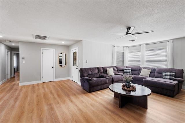 living room with a textured ceiling, light hardwood / wood-style floors, and ceiling fan