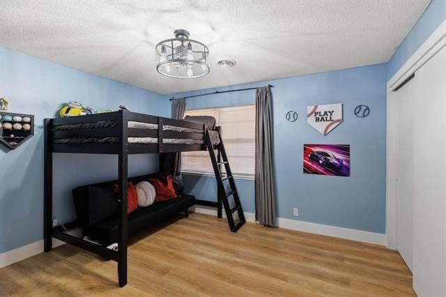 bedroom with wood-type flooring, a textured ceiling, and a notable chandelier