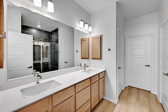 8004 Tranquil Glade Trl, Austin, TX 78744 - bathroom featuring wood finished floors, a stall shower, double vanity, and baseboards